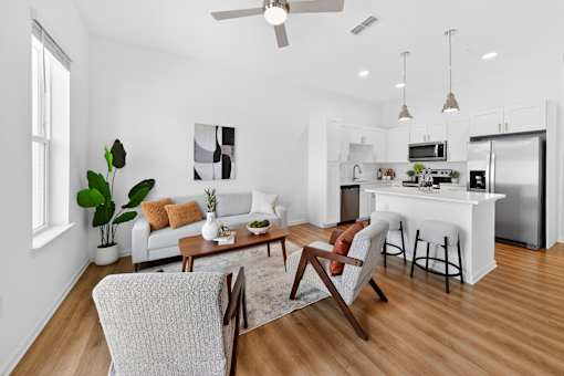 A modern living room with a white sofa, a wooden coffee table, and a white kitchen in the background.