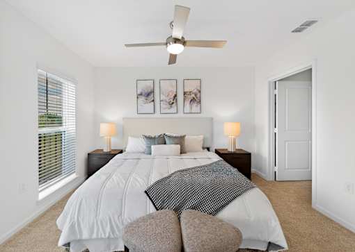 A bedroom with a large bed and a ceiling fan.