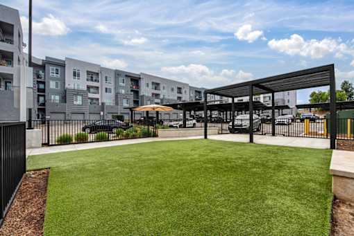 A grassy area in front of a building with a black fence.