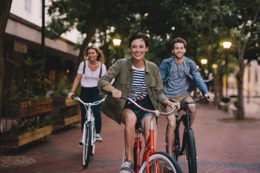 three people riding bikes down a city street