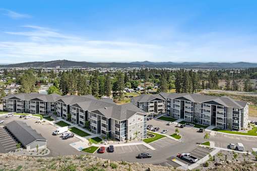 A large apartment complex with a parking lot in front.