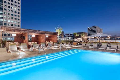 A swimming pool with chairs around it at night.