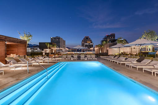 A long rectangular pool with lounge chairs on the side.