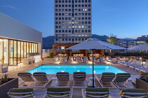 A pool surrounded by lounge chairs and umbrellas.