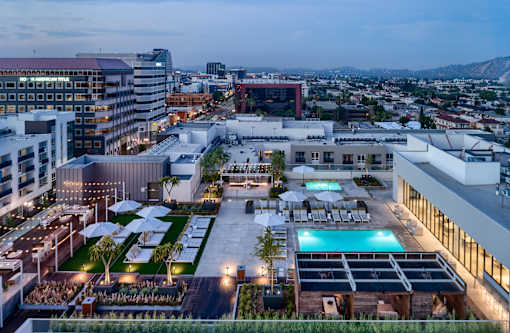 A rooftop pool area with a view of the city at dusk.