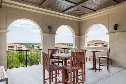 A patio with a table and chairs overlooking a fence.