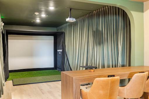 A room with a desk and chairs and a projection screen.