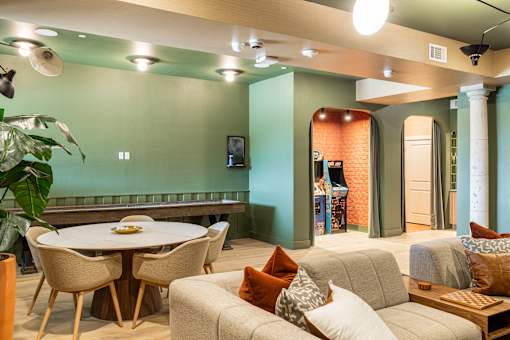 A living room with a white table and chairs, a grey couch, and a green wall.