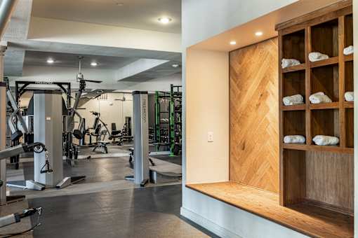 A gym with a variety of equipment and a wooden shelf with towels.