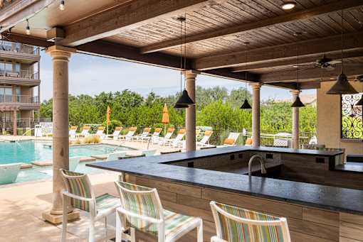 A poolside bar area with striped chairs and a black counter.