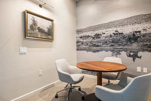 A black and white photo of a cowboy on a horse is on the wall above a wooden table.