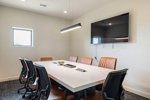 A conference room with a white table and brown chairs.