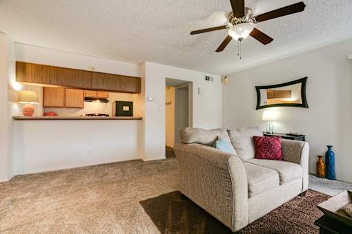 A living room with a beige couch and a ceiling fan.