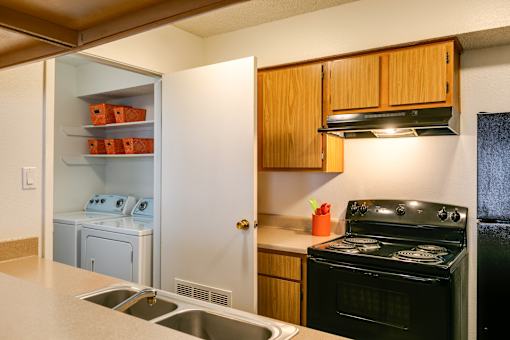 A kitchen with a black stove and wooden cabinets.