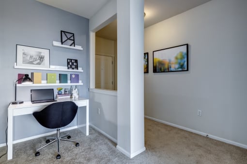 a home office in a bedroom with gray walls and carpet