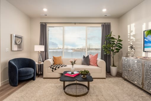 Living room with a blue armchair, a white sofa, a coffee table, and a television.