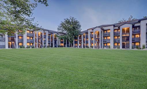 A large grassy area in front of a building with many windows.