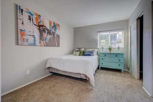 A bedroom with a bed, dresser, and a painting on the wall.