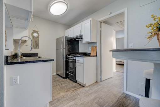 A kitchen with white cabinets and a black countertop.