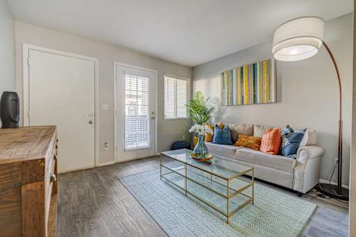 A living room with a white couch and a glass coffee table.