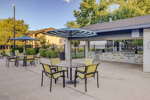 A patio with a table and chairs under an umbrella.