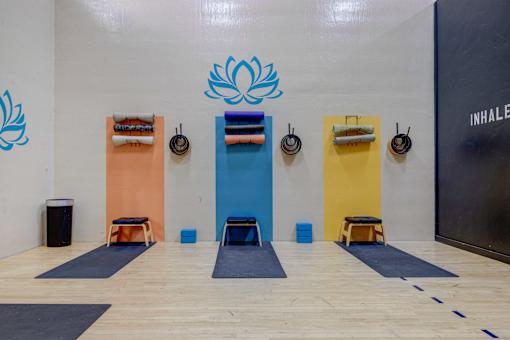 A yoga studio with a wooden floor and a wall with a blue lotus design.