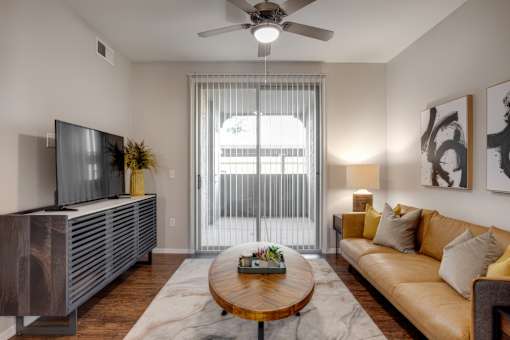 A living room with a brown couch, a wooden coffee table, and a flat-screen TV.