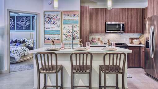A kitchen with a table set for two and a fridge to the right.