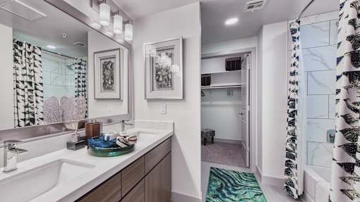 A bathroom with a sink, mirror, and shower.