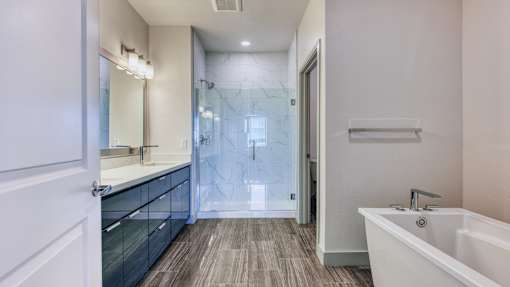 A modern bathroom with a white tub and wooden flooring.