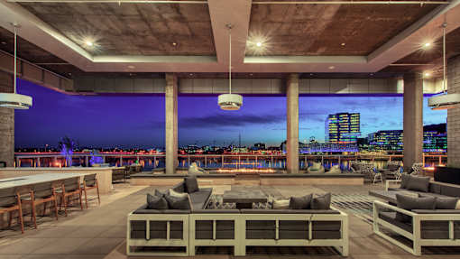 A modern outdoor seating area with a view of the city skyline at dusk.