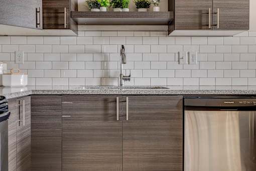 A modern kitchen with a stainless steel dishwasher and wooden cabinets.