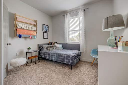 A bedroom with a bed, desk, and chair.