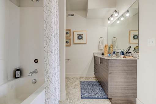 A bathroom with a white tub, a sink, and a mirror.