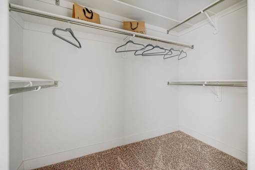 A white closet with a brown carpet and a hanger with a smiley face on it.