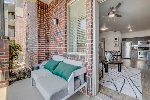 A white couch with green pillows is on a patio.