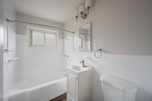 A white bathroom with a tub, sink, and mirror at Hillsdale Garden Apartments, San Mateo, CA 94403