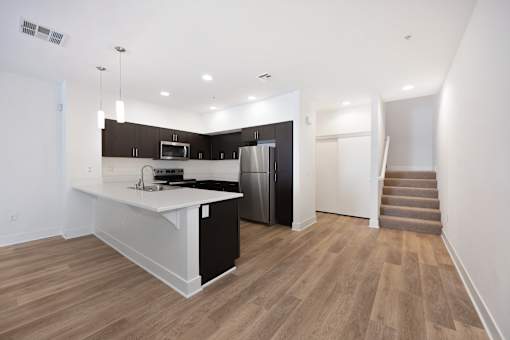 A kitchen with a refrigerator, microwave, and stove top oven at Palomar Station San Marcos, CA apartments for rent.