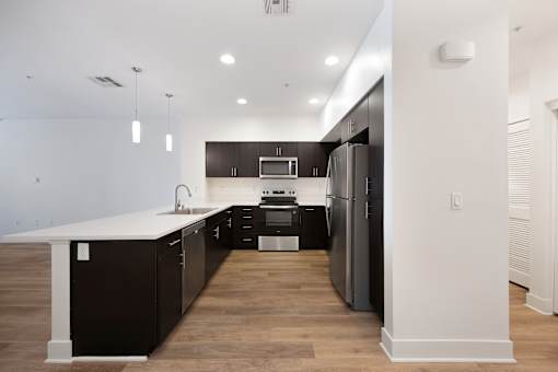 A modern kitchen with dark wood cabinets and stainless steel appliances.