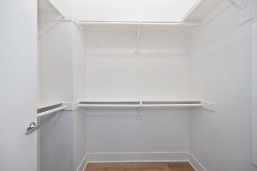 A white closet with a door and a shelf.