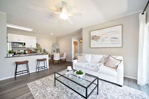 A modern living room with a white couch and a glass coffee table.
