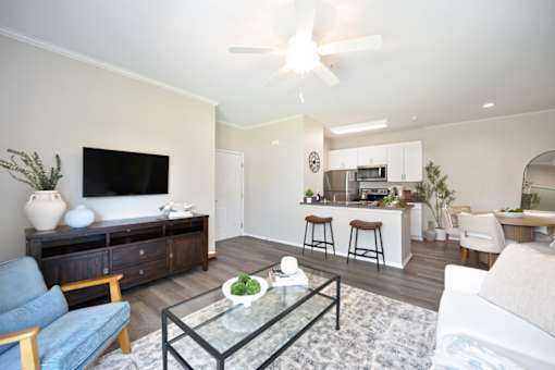 A modern living room with a blue sofa, a glass coffee table, and a flat-screen TV.