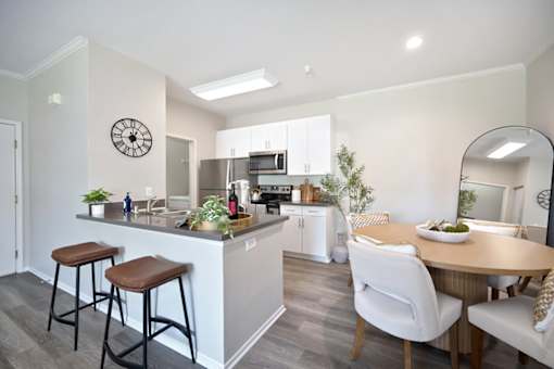 A kitchen with a bar area and a dining table with chairs.