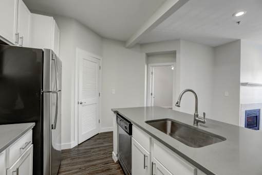 A kitchen with a black refrigerator and white cabinets.