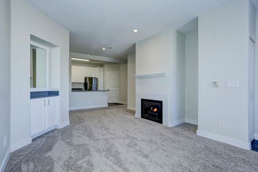 A living room with a fireplace and a grey carpet.