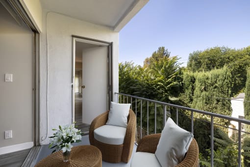 a balcony with two wicker chairs and a table at The Fulton, 91423