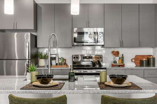 A modern kitchen with a stainless steel refrigerator and a center island with two bowls on top.