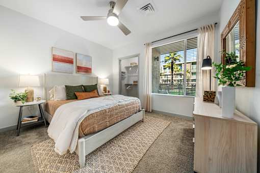 A bedroom with a bed, nightstand, and a plant on the side table.