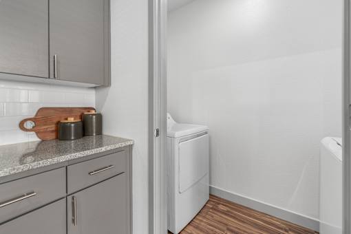 A kitchen with a white dishwasher and grey cabinets.