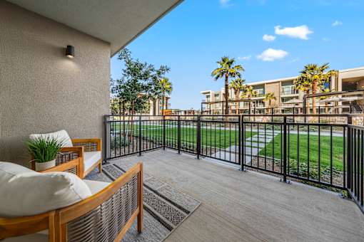 A balcony with a wooden bench and a black railing.
